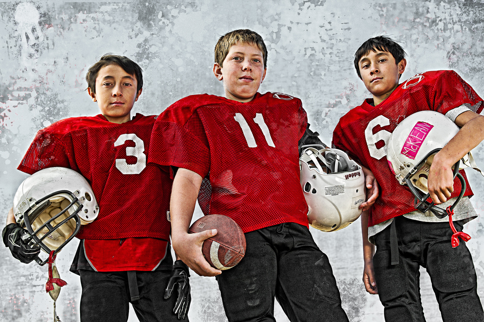 Three young football players in red jerseys looking tough for the camera.