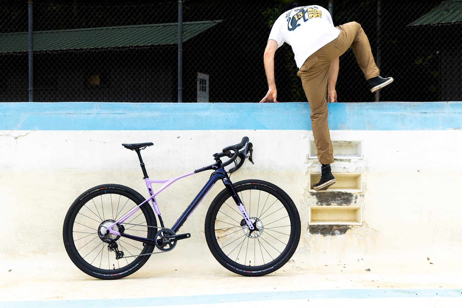 A purple GT Gravel Bike in an abandoned swimming pool - a man climbing out of the swimming pool