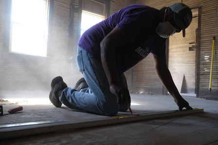 Matt measures a piece of plywood that will be used to frame the new half bathroom.