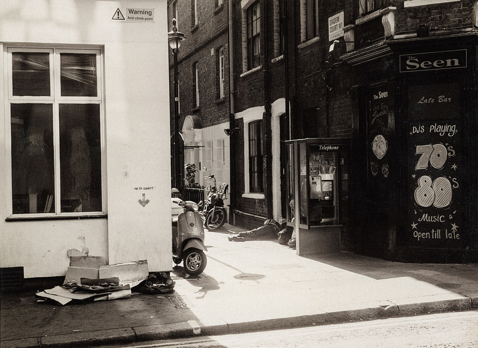 A black and white image of a homeless man asleep behind Tottenham Court Road Station in August 2001.