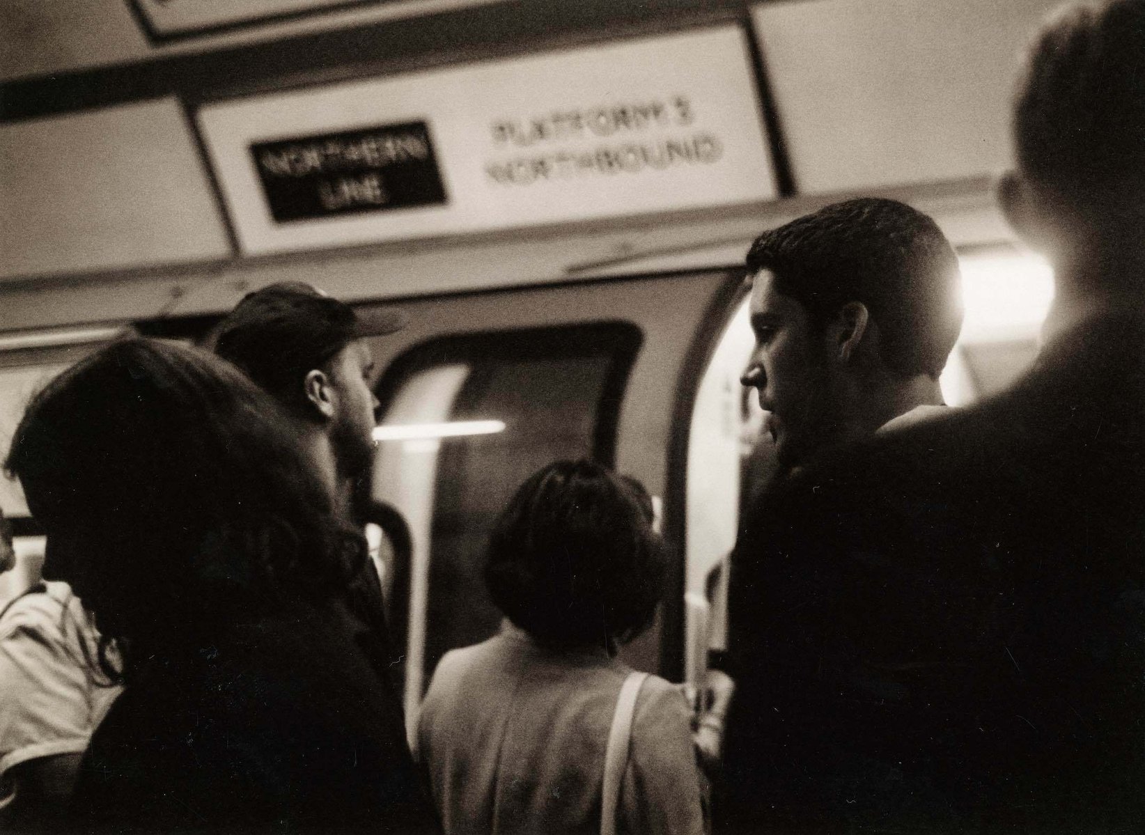 Black and white image of a group of people on a crowded platform at Tottenham Court Road Station, Northern Line, in August 2001.