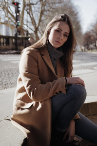 Jeune femme en manteau marron assise sur des marches