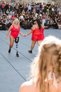 Relai entre deux jeunes femmes dont l&amp;#x27;une avec une prothèse de jambe lors du défilé The All Sizes Catwalk à Paris en septembre 2019