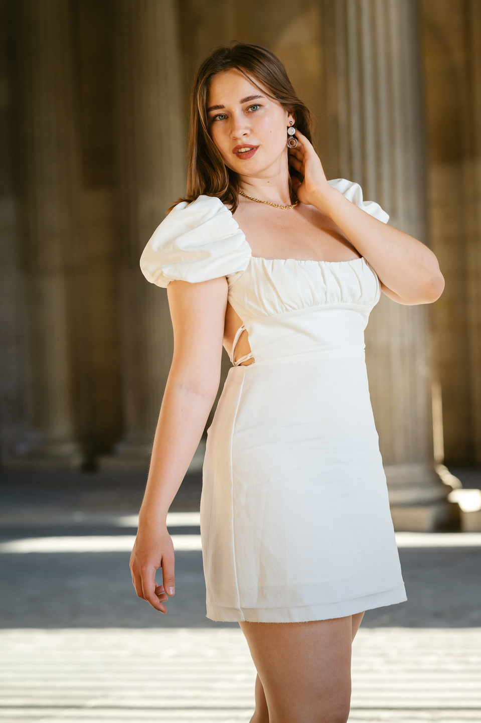 Jeune femme en robe blanche devant des colonnes