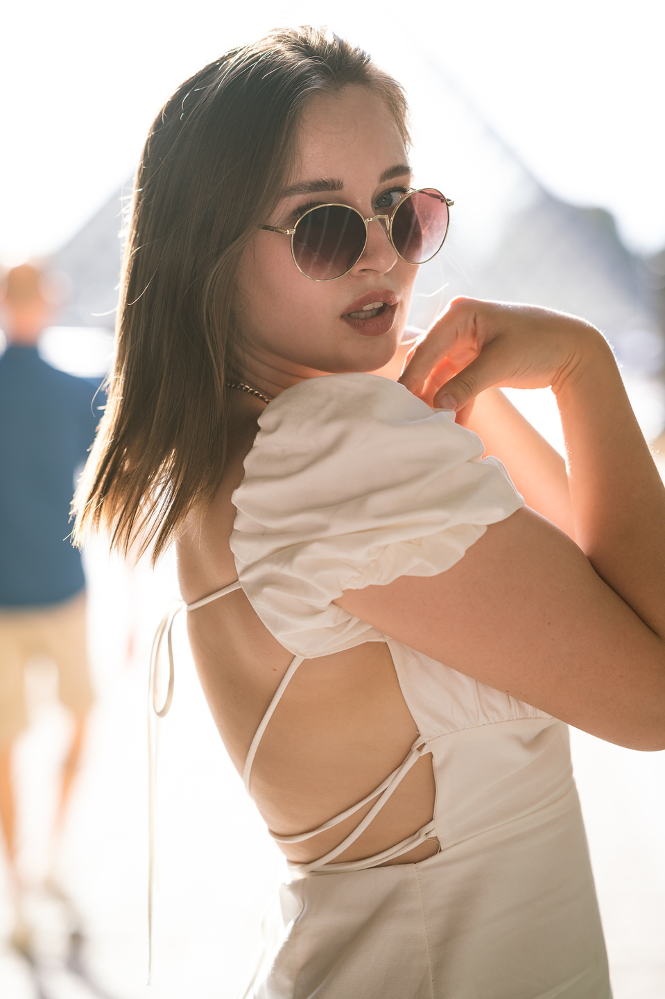 Jeune femme à lunettes devant la pyramide du Louvre à Paris