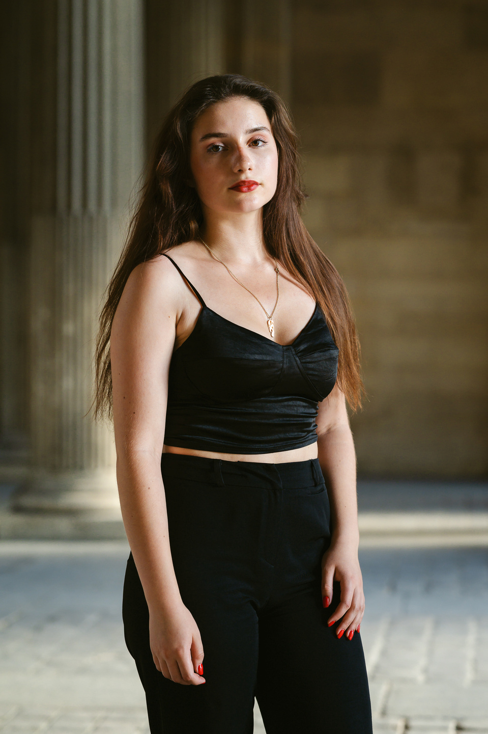 Jeune femme habillée en noir devant une colonne