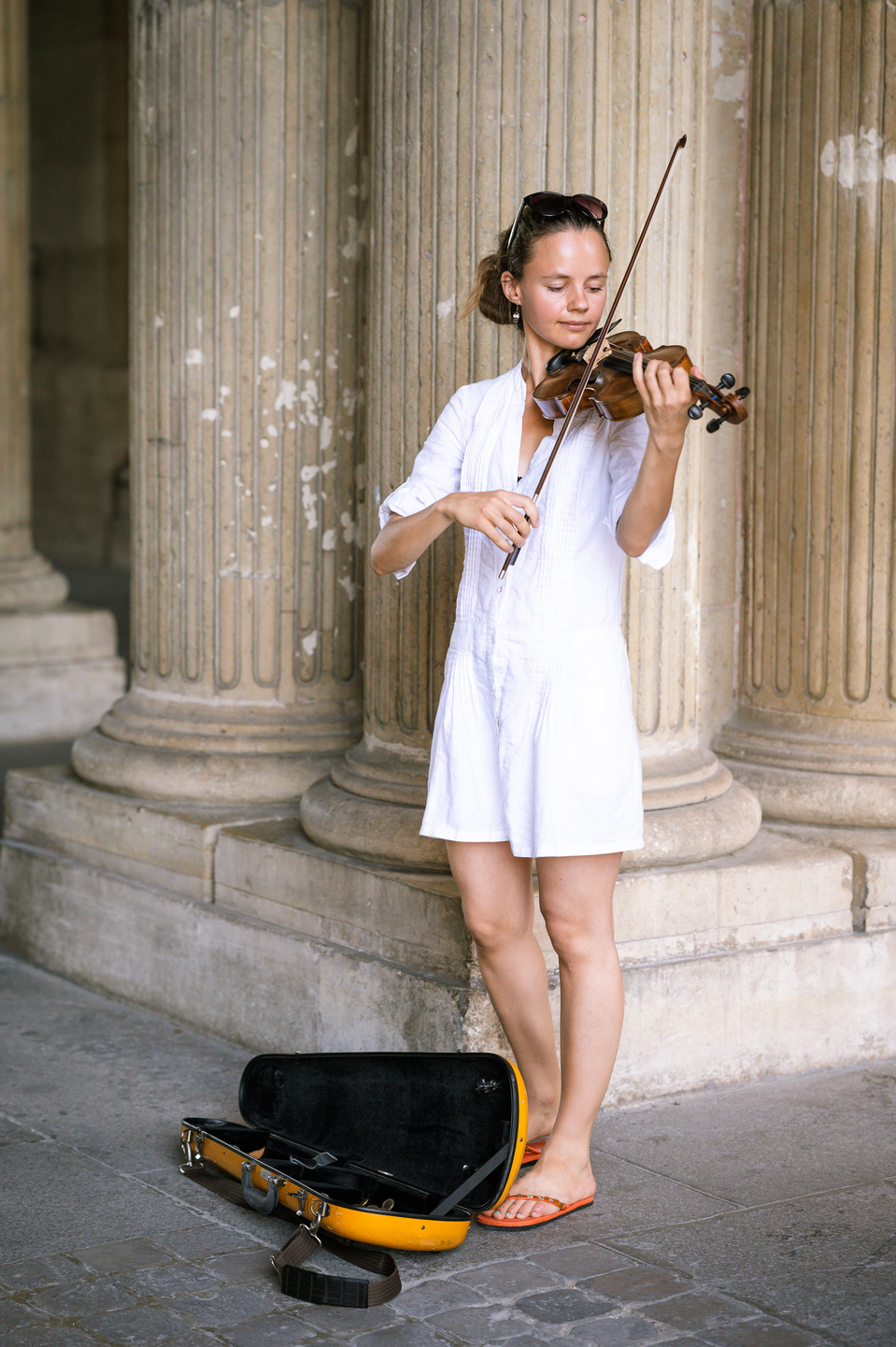 Violoniste en robe blanche devant des colonnes
