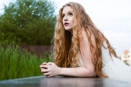 Jeune femme en robe blanche avec une longue chevelure rousse