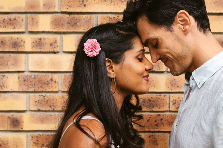 Photo d'un couple amoureux devant un mur de briques