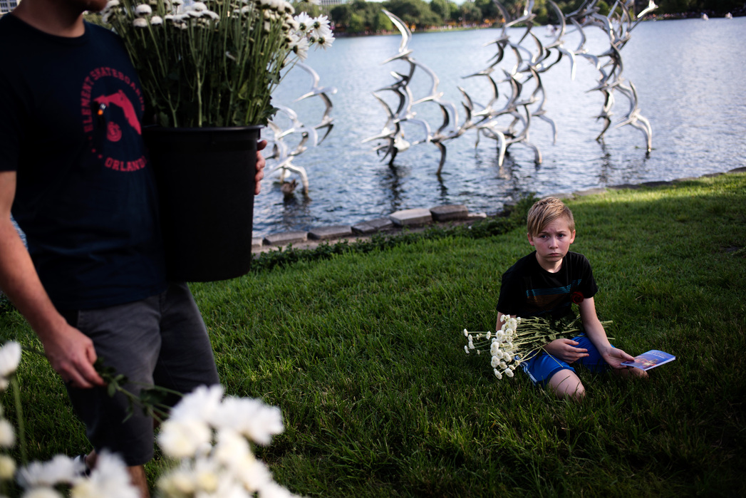 ORLANDO, FLORIDA- JUNE 19, 2016: Ryan Ponder, left, and his son Caeden Ponder, 11, hand out flowers at the vigil at Lake Eola for Pulse Nightclub where a massacre occurred a week earlier leaving 49 people dead.