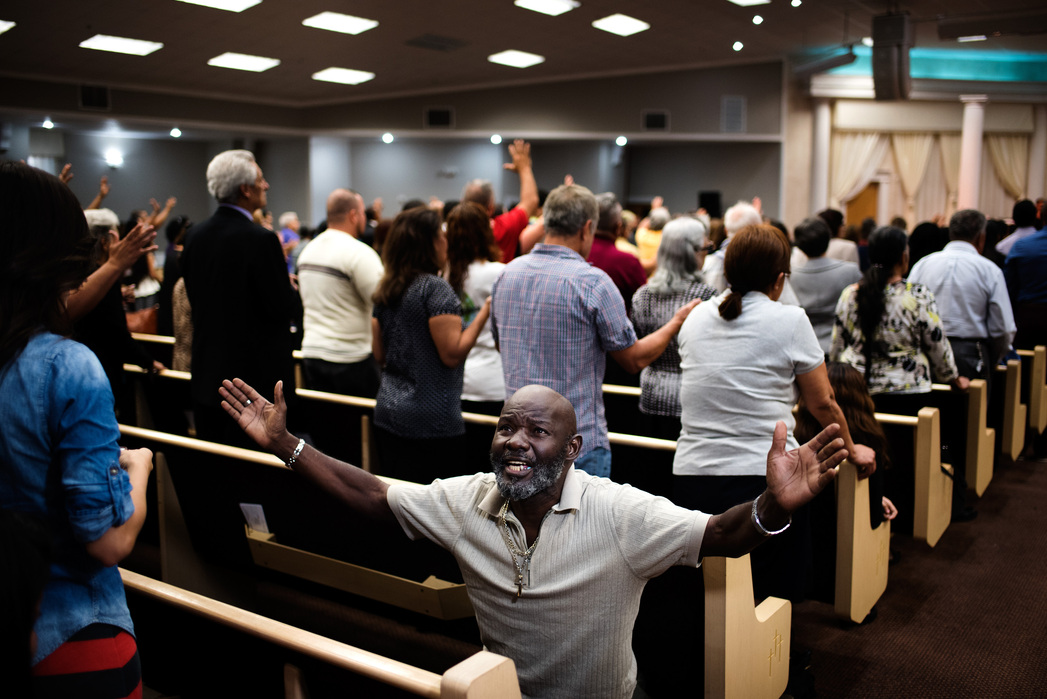 ORLANDO, FLORIDA- JUNE 15, 2016: A member of the Igesia de Dios Pentecostal Church reacts to a service on Wednesday while a film crew points their camera light at him. A prevalent topic at the service was the Pulse Nightclub massacre which on Sunday morn