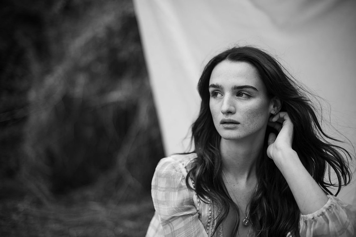 A portrait of a lady in black and white. The wind is blowing her hair and she is looking away from the camera. 