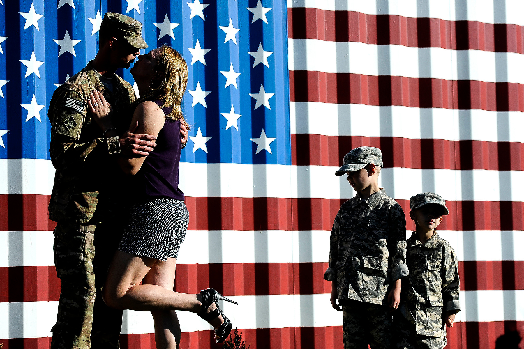 Michael Pfaff, 6, second from right, and Gabriel Pfaff, 3, right, watch as their parents, Spc. Jonathan Pfaff and Tara Pfaff kiss for a photo after Jonathan returned home from Afghanistan with about 150 soldiers of the 4th Brigade Combat Team Wednesday, A
