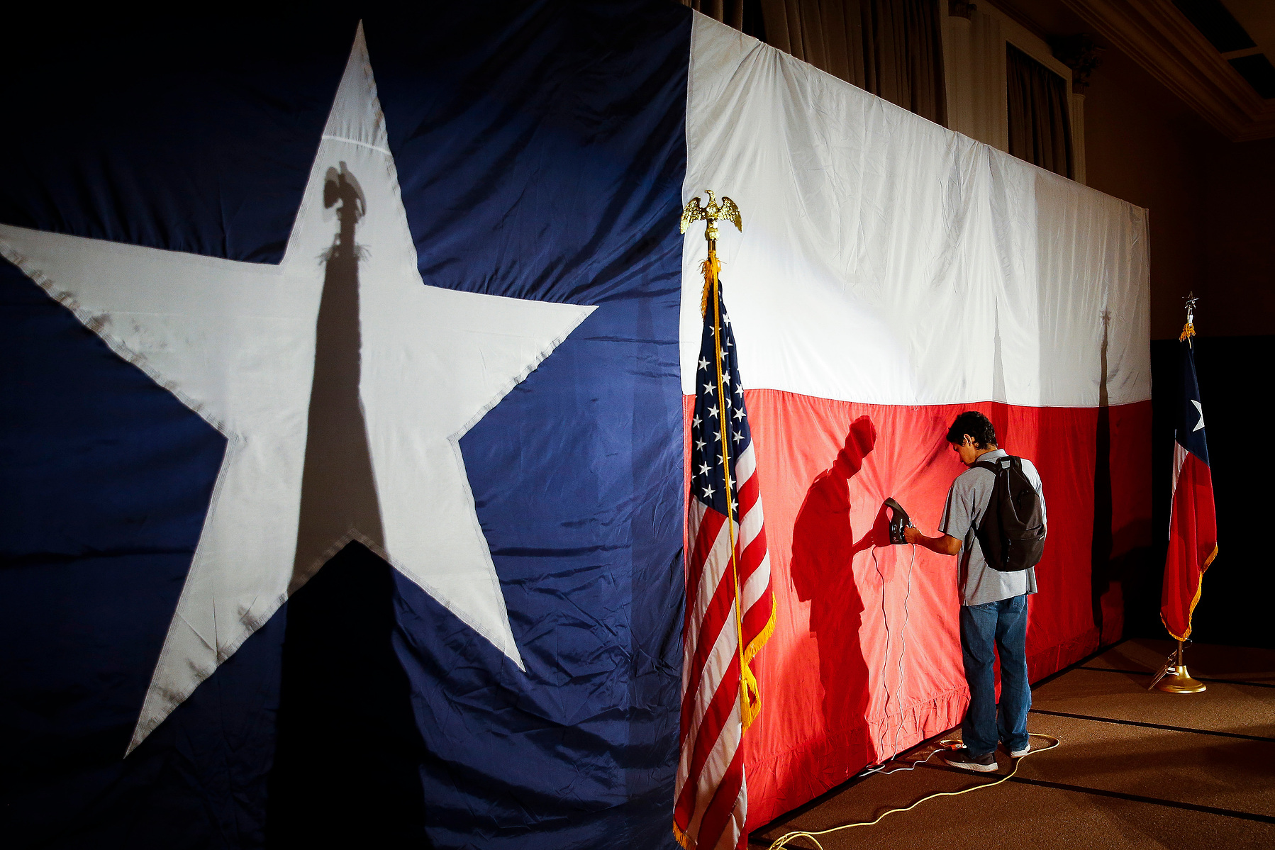 Intern for the Ted Cruz campaign Jose Maybit Lopez steams a giant Texas flag behind the stage at the election night event for the senator at the Hilton Post Oak Ballroom Tuesday, Nov. 6, 2018, in Houston.