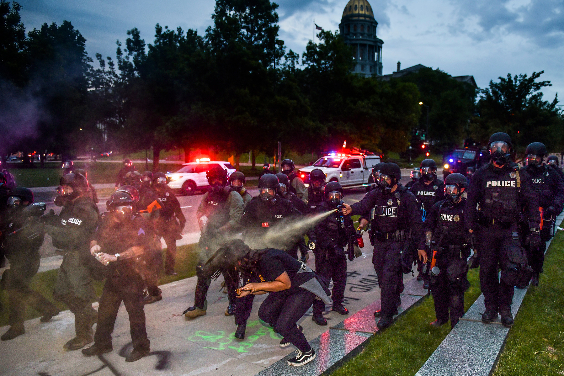 DENVER, CO - MAY 30: Police officers pepper spray a woman next to the Colorado State Capitol as protests against the death of George Floyd continue for a third night on May 30, 2020 in Denver, Colorado. The city of Denver enacted a curfew for Saturday and