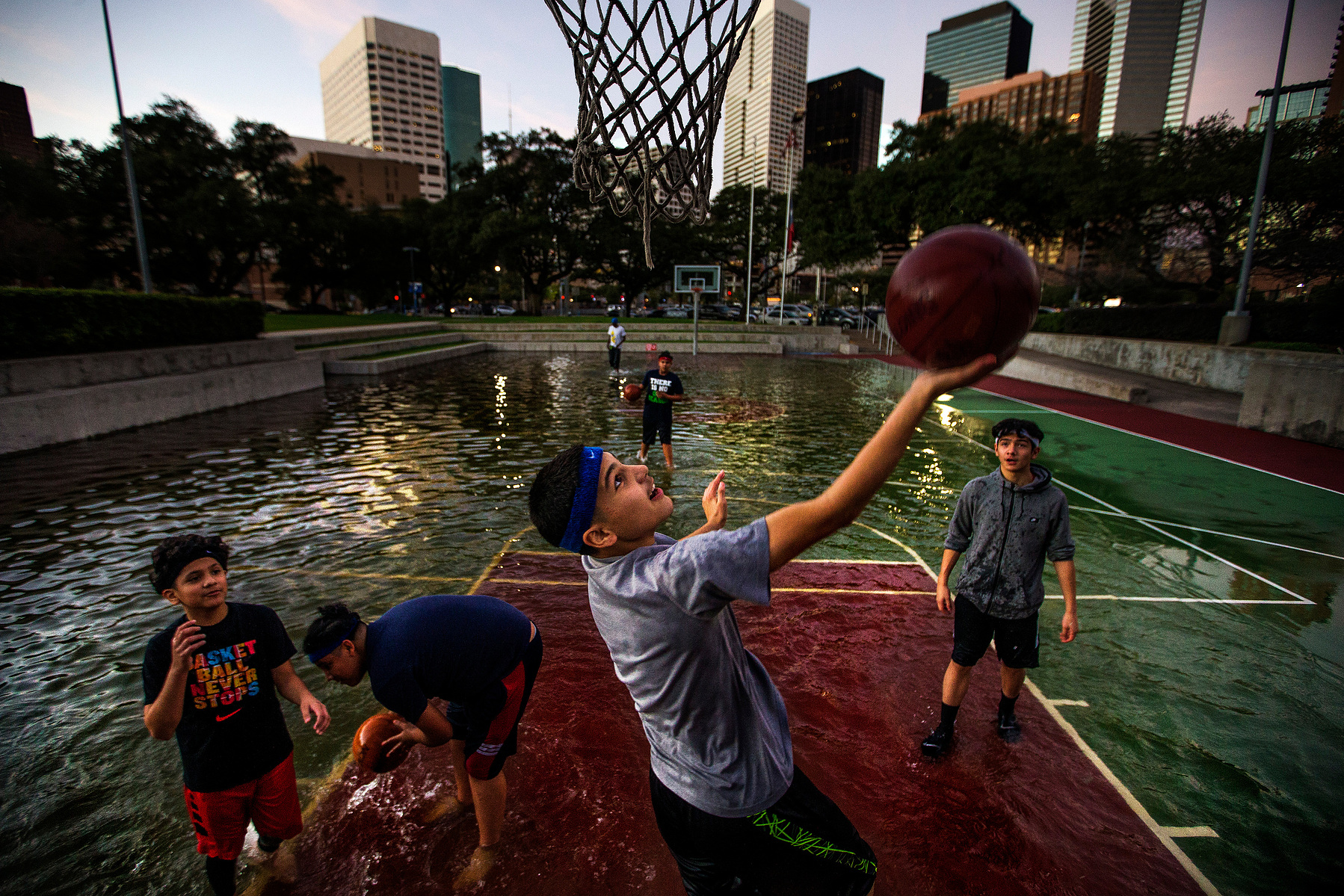 Angel Charles, 13, drives to the hoop as he and his friends play basketball in a court filled with rain water from the morning's storms outside the Toyota Center where the Houston Rockets are set to take on the Washington Wizards Monday, Jan. 2, 2017 in H