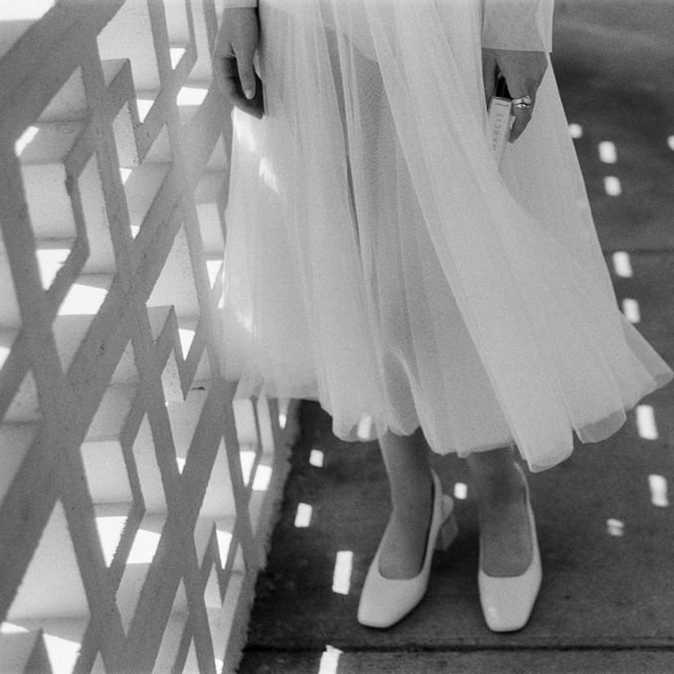 natural light reflected on ground and on woman in white translucent dress and white heels