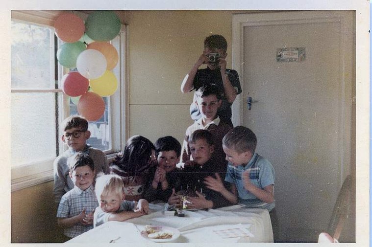 Here I am at age 10 standing on a chair taking a photo of the adults at my brother's birthday party. I am using a Kodak Instamatic Camera. 
