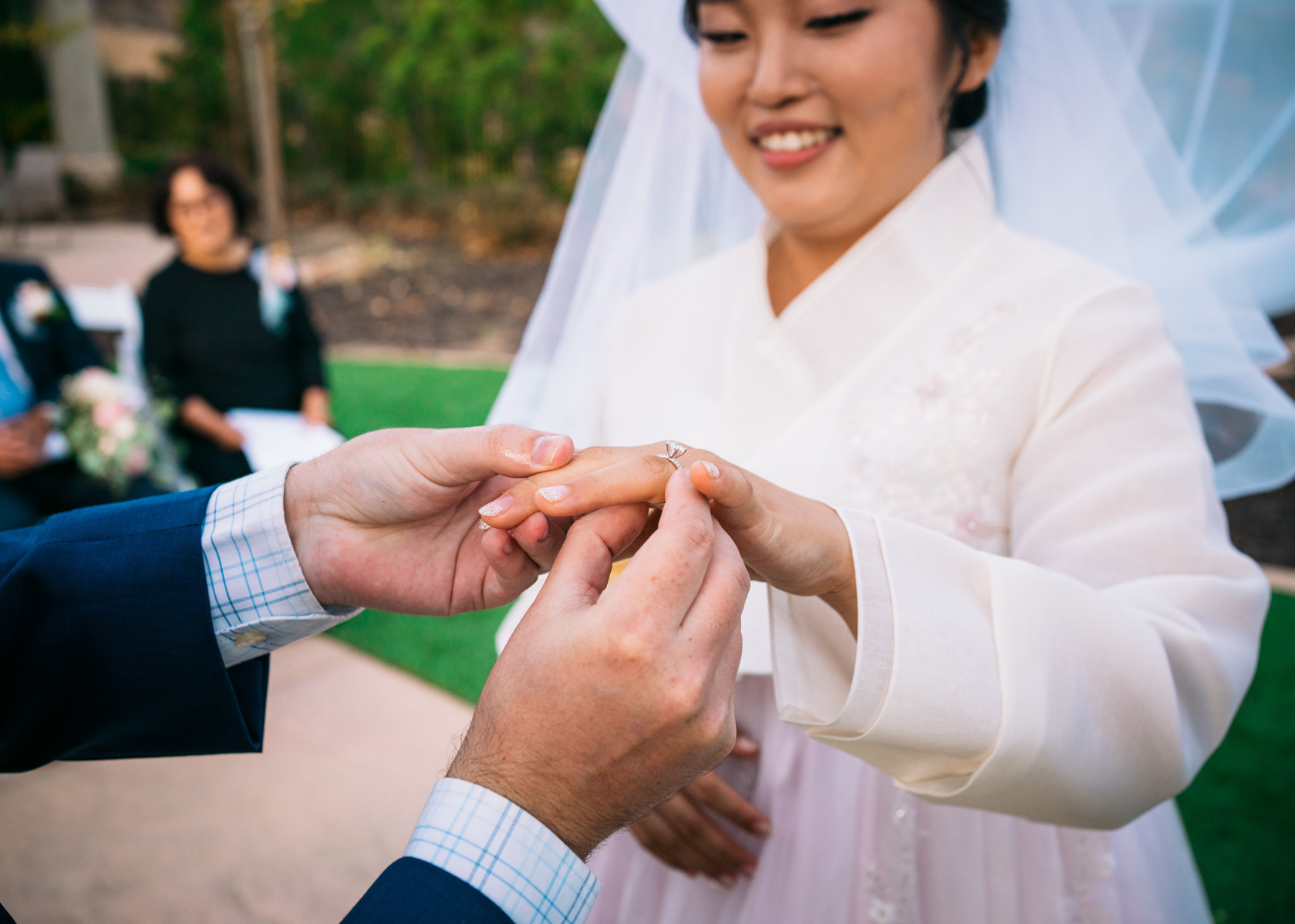 groom puts the wedding ring on the smiling brides finger