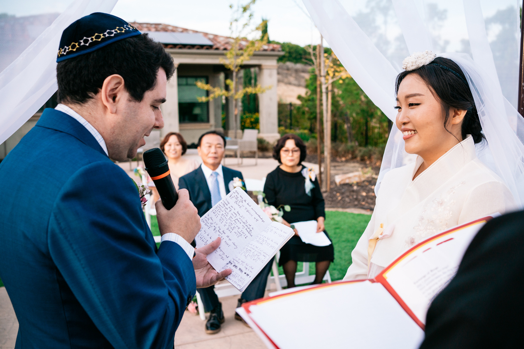 groom reads his vows in english and korean while his bride smiles