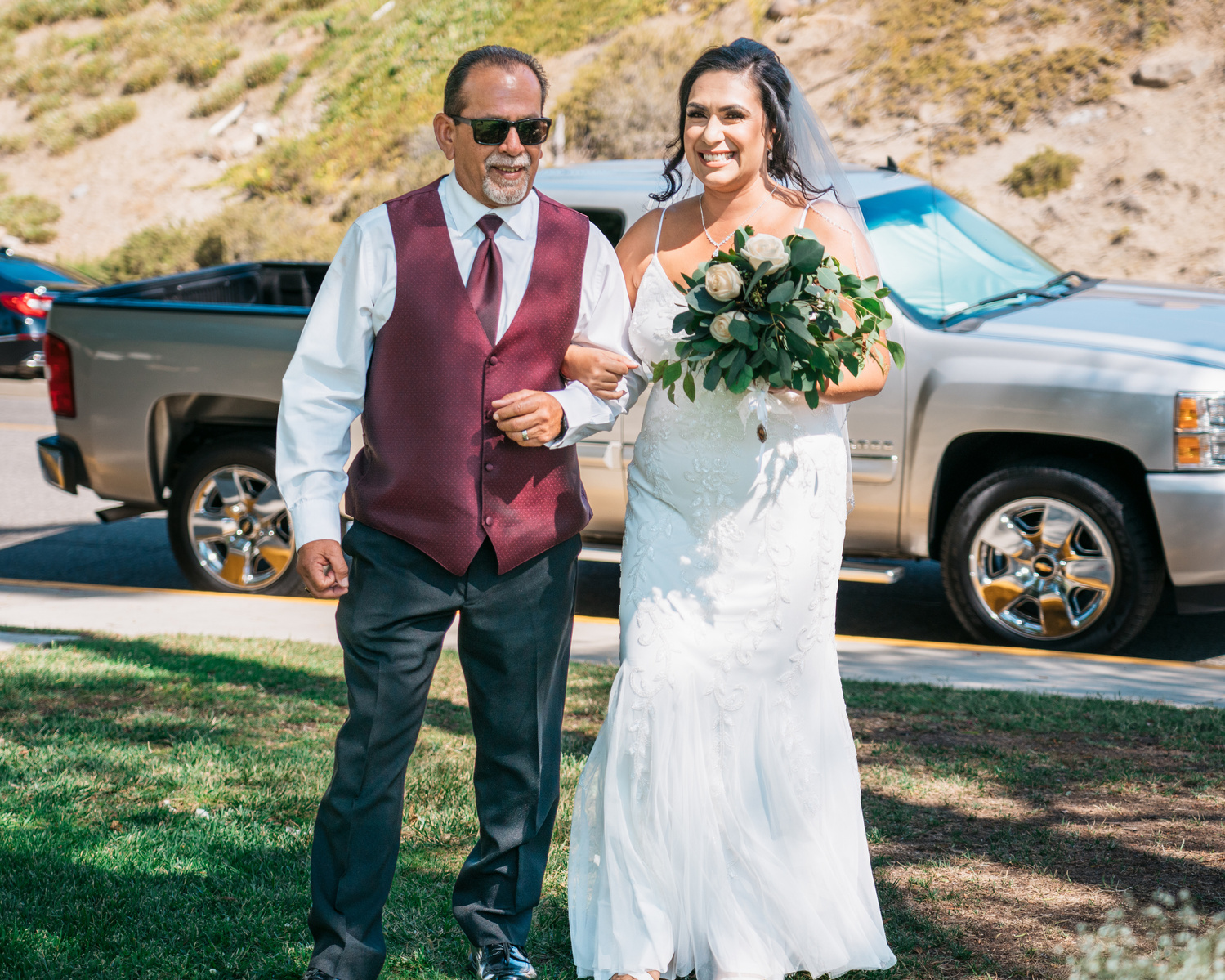 smiling bride arm in arm with her smile father 