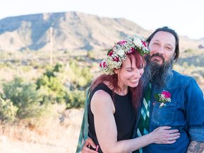 boho wife laughs in wedding portrait at a desert elopement with a mountain in the background in pioneertown california