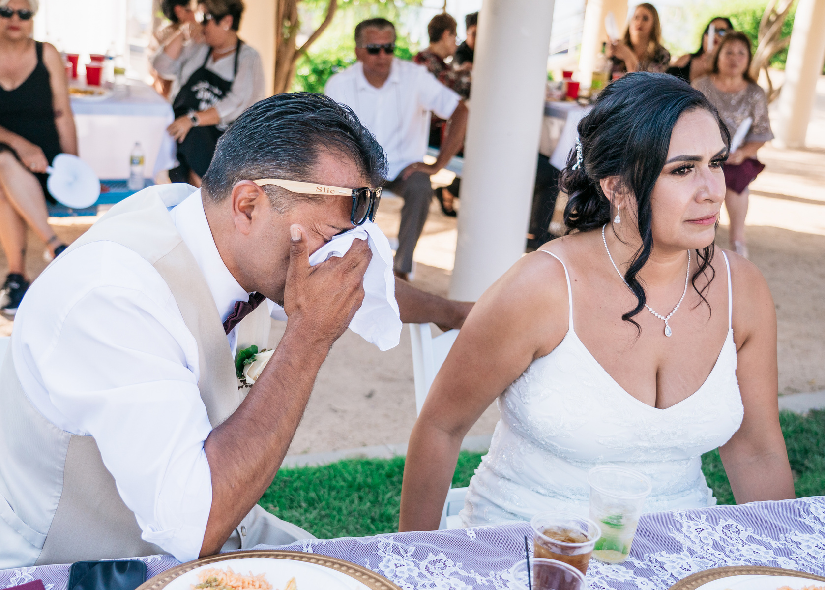 groom wipes away tears while bride consoles him