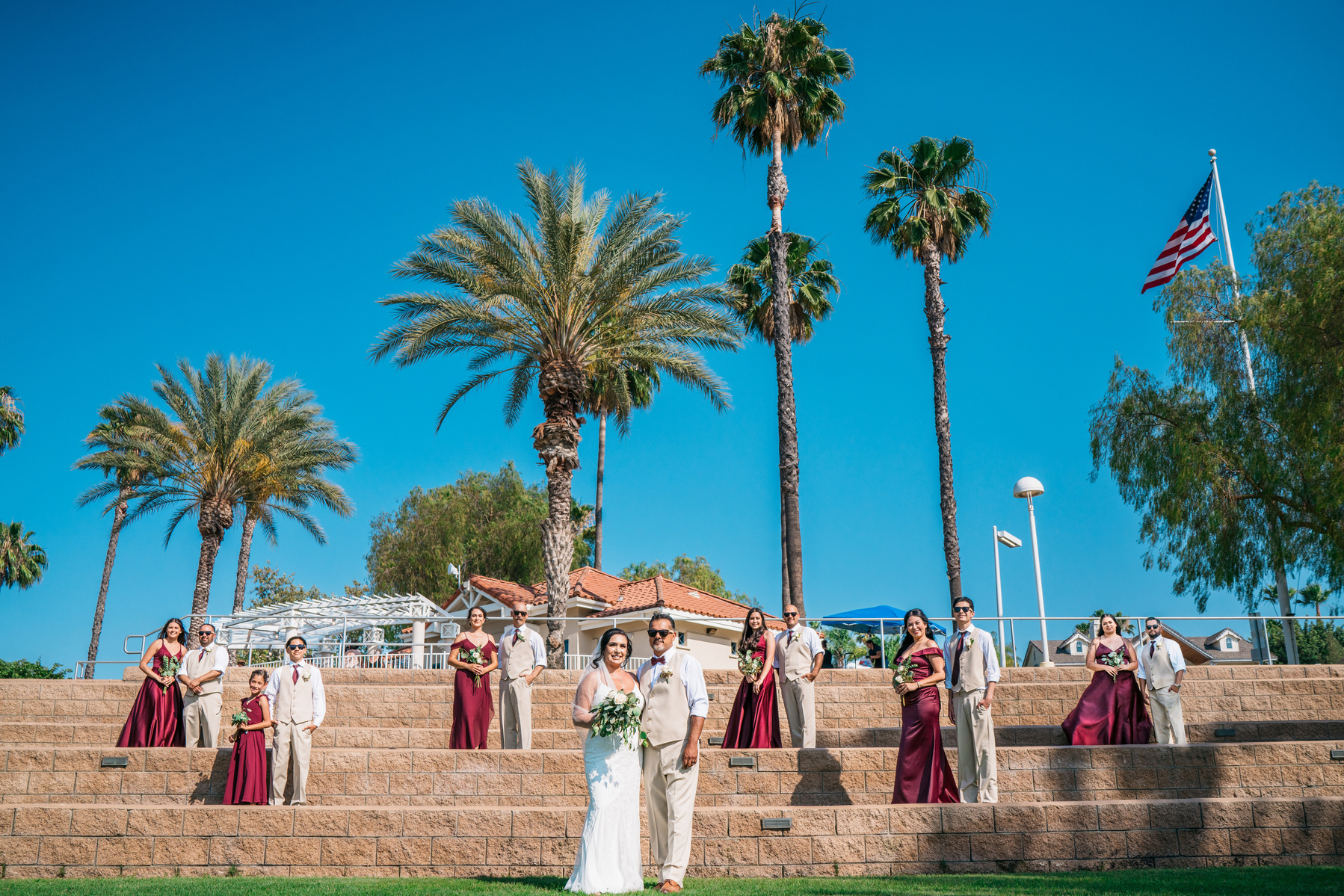 vanity fair style grand bridal party portrait with bride and groom palm trees and american flag canyon lake california wedding photography temecula southern california