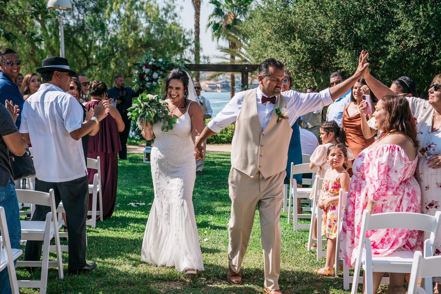 as the bride and groom walk back down the aisle smiling high five guest 