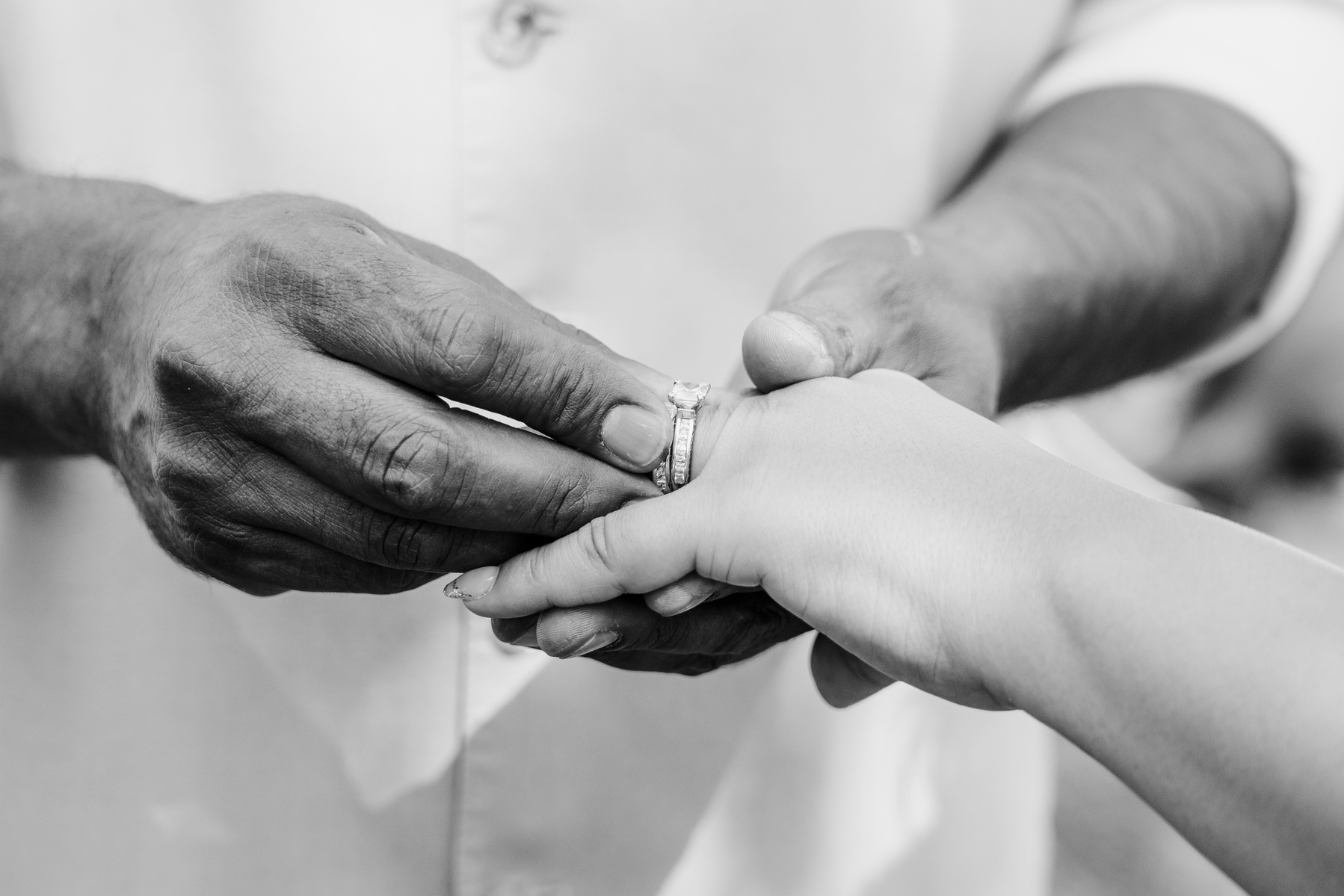 black and white groom puts wedding band ring on his brides finger