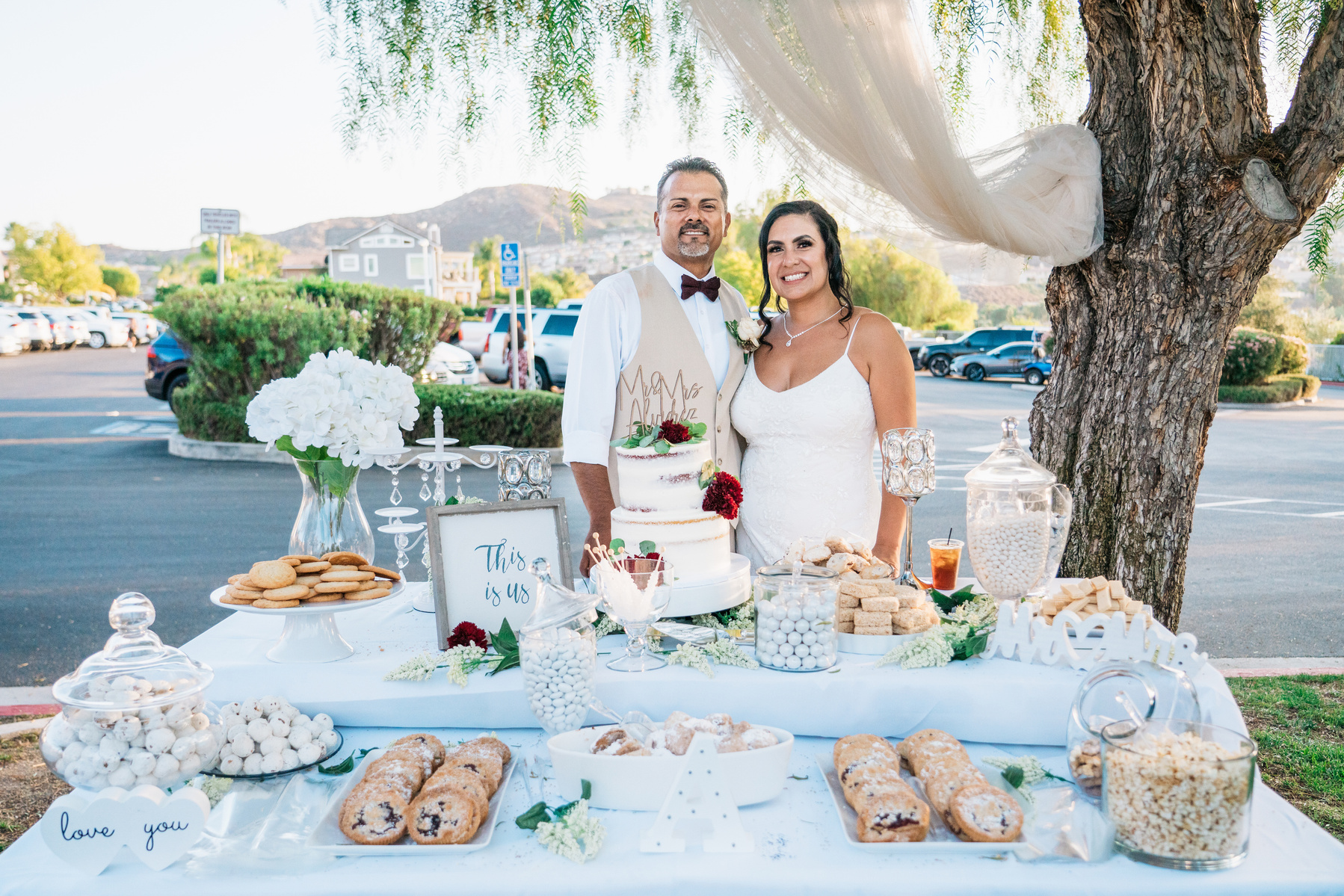 groom and bride husband and wife pose at the sweets table