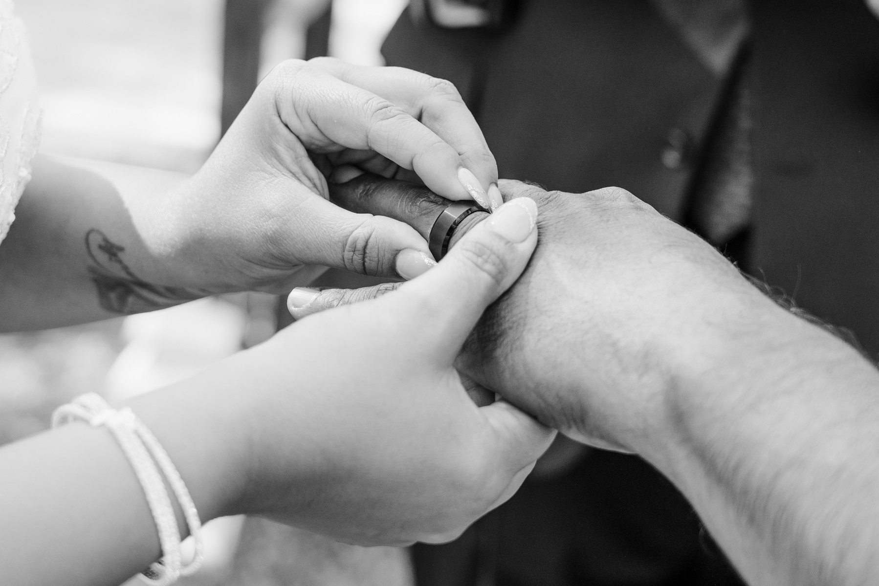 black and white bride puts ring on grooms finger