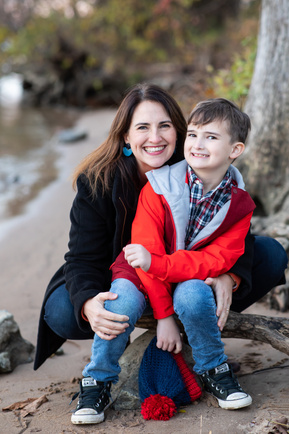 A natural light photograph of a mom hugging her young son by the waters edge.