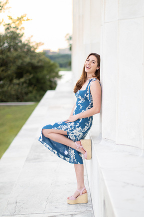 A teenage girl laughing and leaning against the Lincoln Memorial at sunset in Washington DC.