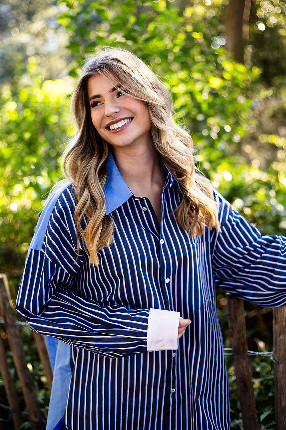 Portrait d'une jeune femme blonde habillée en bleu devant un buisson lors d'une séance photo à Toulouse.
