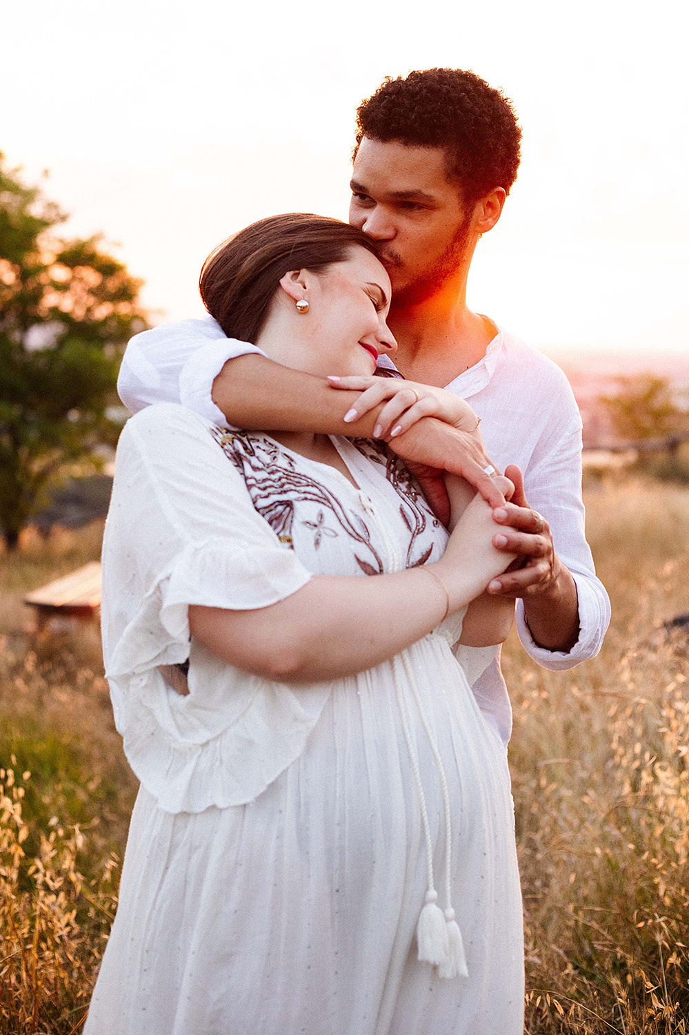Un couple de jeunes gens se font un câlin dans le soleil couchant lors d'une séance photo à Pech David à Toulouse.