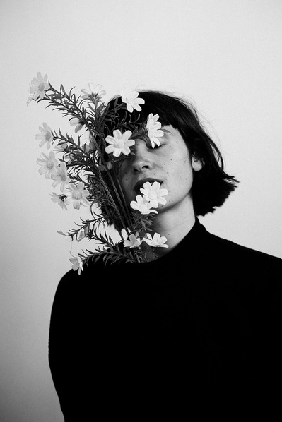 Portrait artistique en noir et blanc d'une femme en studio, lumière douce et fleurs  – Photographe à Toulouse