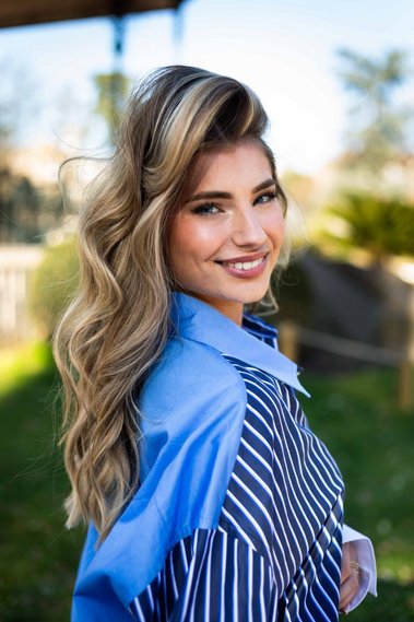 Jeune femme souriante en chemise dans un jardin.