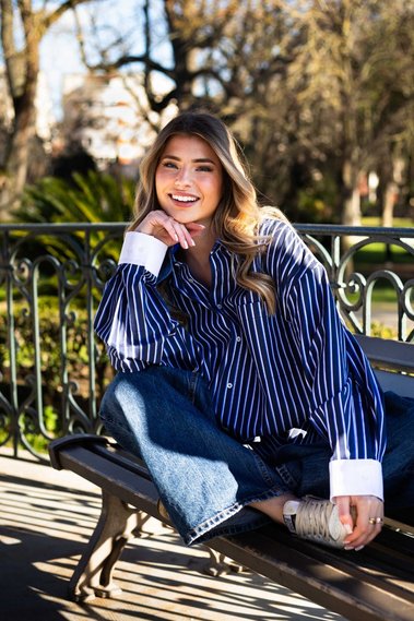Jeune femme souriante en chemise dans un jardin.