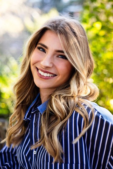 Jeune femme souriante en chemise dans un jardin.