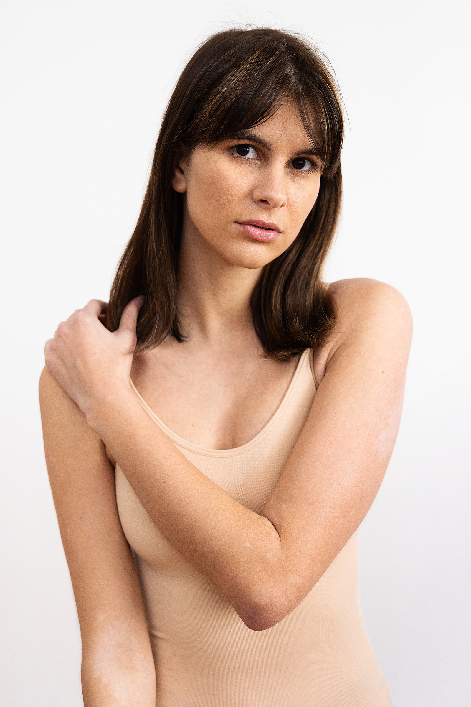 Une jeune femme mannequin avec un justaucorps beige pose en studio lors d'une séance photo polas à Toulouse.