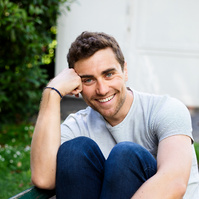 Portrait d'un jeune homme souriant sur un banc au jardin des plantes - Photographe à Toulouse