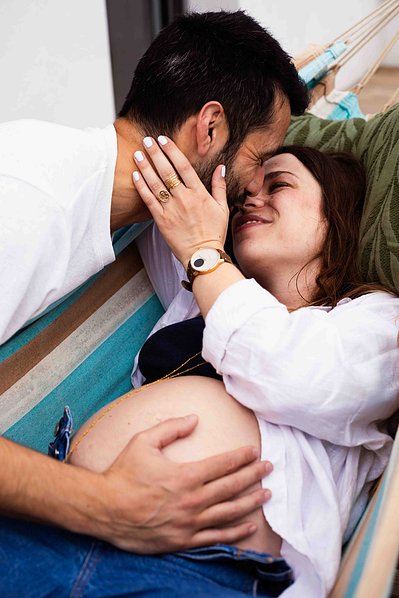 Une femme enceinte embrasse tendrement son mari lors d'une séance photo grossesse à Toulouse