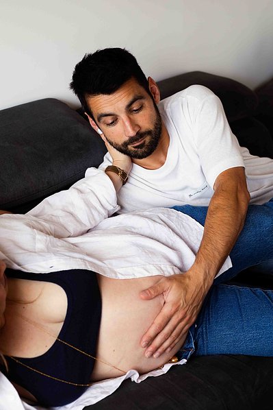 Un futur papa regarde et touche le ventre rond de sa femme lors d'une séance photo grossesse à Toulouse