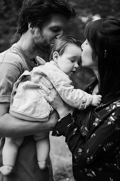 Des parents embrassent leur bébé tendrement en fermant les yeux lors d'une séance photo famille à Toulouse.