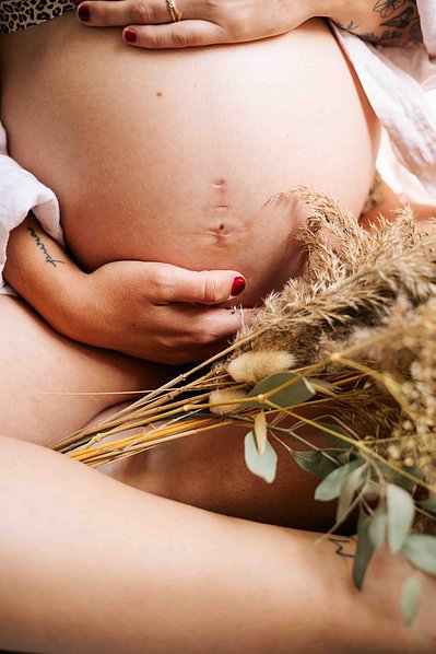 Le ventre d'une femme enceinte avec un bouquet de fleurs séchées lors d'une séance photo grossesse à Toulouse