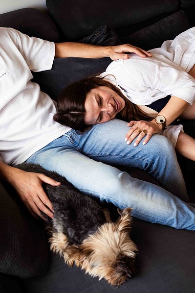Un couple passe un momen tde complicité avec leur petit chien sur le canapé lors d'une séance photo grossesse à Toulouse