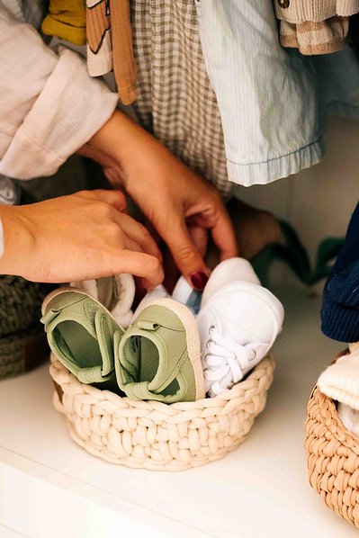 Des petites chaussures de bébés sont dans un petit panier en osier lors d'une séance photo grossesse à Toulouse
