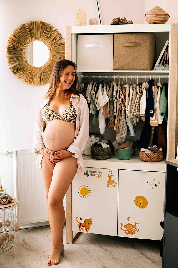 Femme enceinte qui est debout dans une chambre de bébé lors d’une séance photo grossesse  à Toulouse