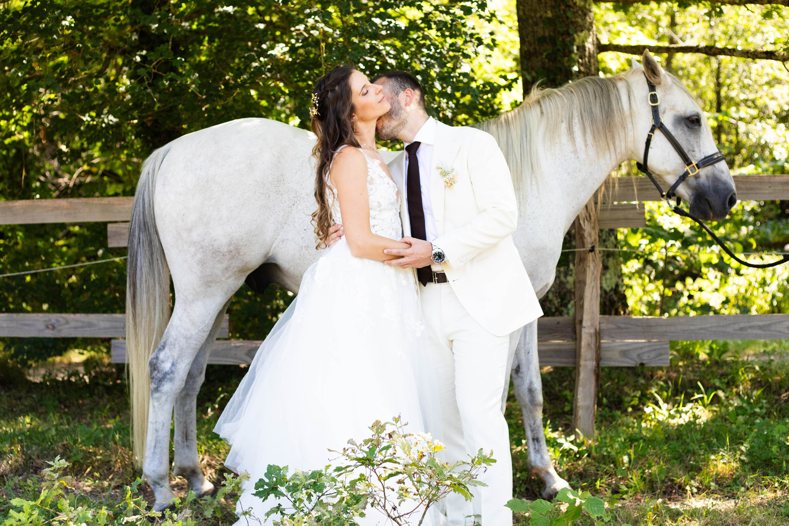 Portrait complice de deux mariés près d'un cheval pendant la séance photo de couple, réalisé par Ines Pochelu, photographe à Toulouse
